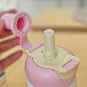 Detail shot of the pink and beige thermos straw lid, showing clean double-drink cap structure.