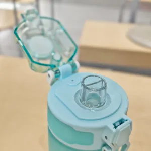 Detail close-up view of the portable light blue plastic water bottle straw lid and spout.