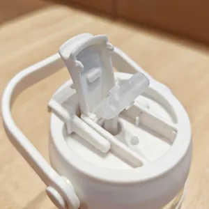 Close-up detail of white plastic water bottle cap with straw and portable handle.