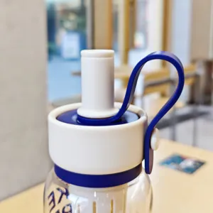 Gros plan sur le bouchon de la bouteille de sport portable, poignée bleue et design de paille.