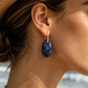 Close-up of teardrop blue stone earrings worn by model, showing elegant vintage metallic details.