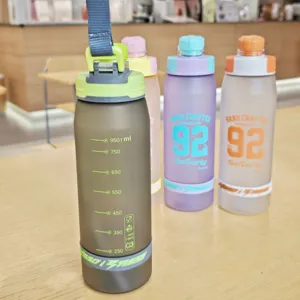 Matte plastic sports water bottle with capacity scale, portable strap for outdoor fitness.