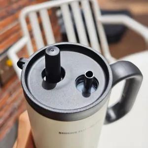 Detailaufnahme des Edelstahltumblers mit doppelem Strohhalmdeckel und schwarzem Griff.