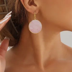 Close up detail shot of elegant gold rimmed round pink stone drop earrings worn by model.