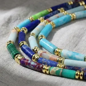 Nahaufnahme von bunten zylindrischen Edelsteinperlen mit Goldabstandshaltern für Schmuck.