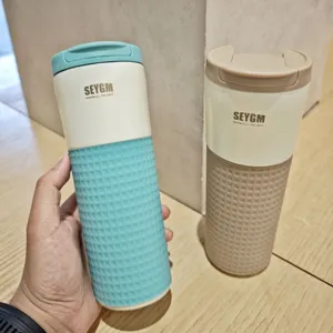 Stainless steel coffee travel mug with silicone sleeve and lid, detail product shot.