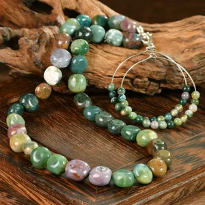 Close-up details of natural stone beaded necklace and hoop earrings set on rustic wood backdrop.
