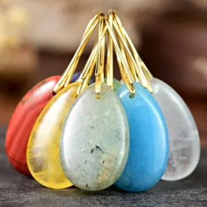 Closeup of colorful teardrop gemstone pendants with golden hooks, exquisite jewelry details.