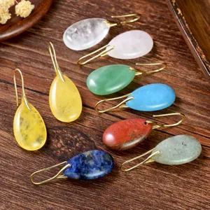 Detailed shot of colorful natural stone teardrop earrings with metal hooks on wooden background.