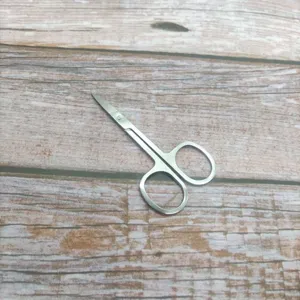 Ciseaux à sourcils cosmétiques en acier inoxydable, détail de pointe incurvée pour la coupe.