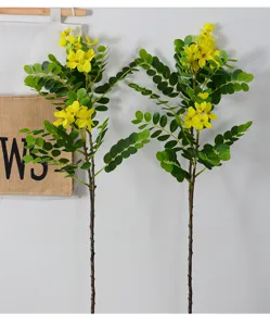 Vue détaillée de branches de fleurs de cassia jaunes artificielles, feuillage vert luxuriant.