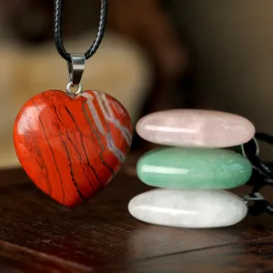 Closeup shot of a vibrant red agate heart pendant necklace paired with stacked gemstone display.