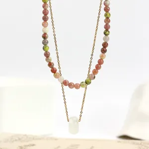 Primo piano di collana di perle in pietra naturale a strati con catena dorata e pendente.