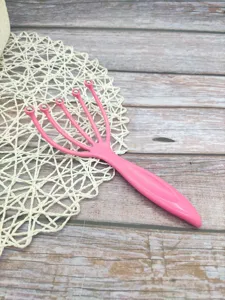 Detaillierte Nahaufnahme eines pinken Fünf-Klauen Kopfmassagegeräts mit silbernen Metallkugeln.