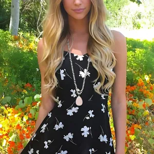 Detail shot of the bohemian teardrop natural stone pendant necklace worn by a model in floral dress