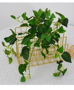 Artificial green ivy vine plant in gold wire rack for home wall decor and indoor styling.