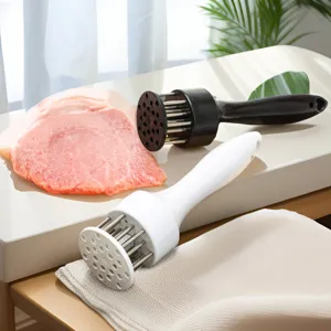 Gros plan de l'outil d'assouplissement de viande avec aiguilles en acier inoxydable et viande.