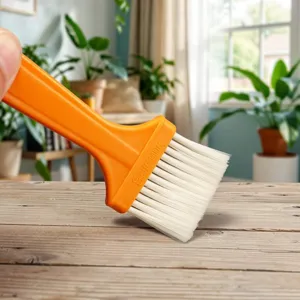 Plastic pastry brush with orange handle and white bristles for baking, BBQ and kitchen cleaning.