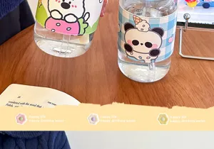 Nahaufnahme Detail der süßen Cartoon Glas Trinkflasche mit Lederschutzhülle und Strohhalm.