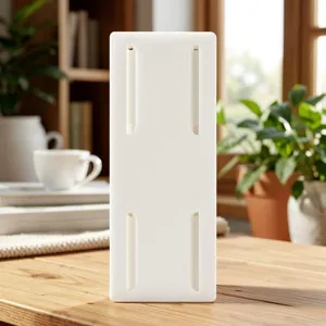 Detail view of the white plastic punch-free wall-mounted power strip fixator clip on a wooden desk.