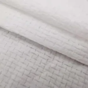 Close-up detail of white waffle textured disposable compressed facial towel for travel.