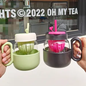 Detail shot of dual-drink glass tea cup with infuser straw and silicone sleeve in daily use.