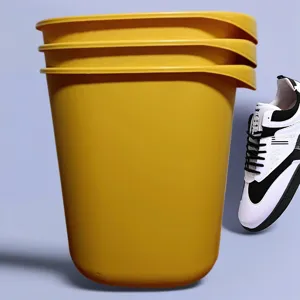 Vista dettagliata che mostra un secchio di plastica giallo e una sneaker nera e bianca.