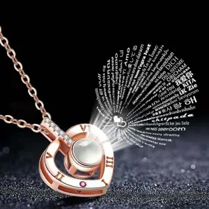 Detailed view of rose gold heart Roman numeral projection necklace showing 100 languages love.