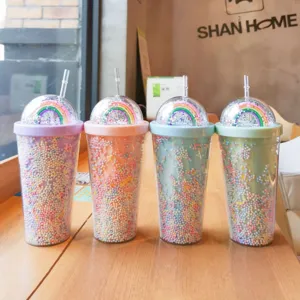 Detailansicht kreativer Regenbogen Plastik Trinkbecher mit doppelwandigen Perlen auf dem Tisch.