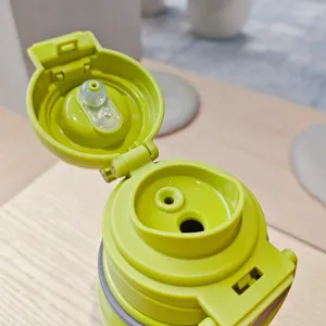 Nahaufnahme des Deckels der grünen Vakuum-Isolierflasche mit dualem Trinkdesign für unterwegs.