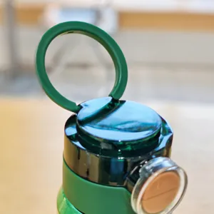 Green plastic water bottle cap detail showing portable handle and dual drinking structure.