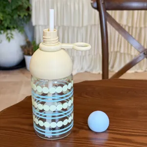 Detailansicht der stilvollen Glas-Wasserflasche mit Strohhalm, rundem Deckel und gepunktetem Design.