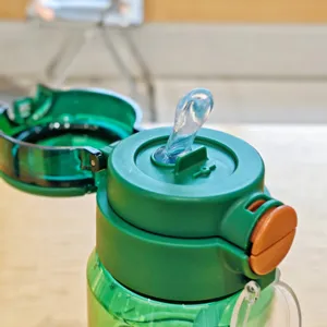 Close-up detail of the green plastic water bottle lid and pop-up straw mechanism.