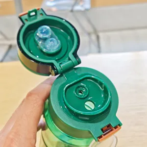 Detail shot of green plastic water bottle lid, dual drinking straw design, outdoor sports cup.