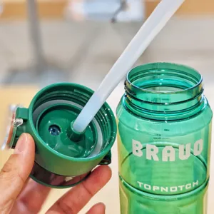 Green plastic straw water bottle detail, portable outdoor sports cup with scale and lid.