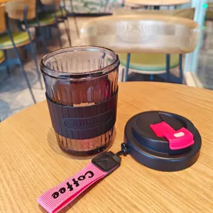 Portable glass coffee cup with silicone sleeve and lid, heat-resistant travel water cup.