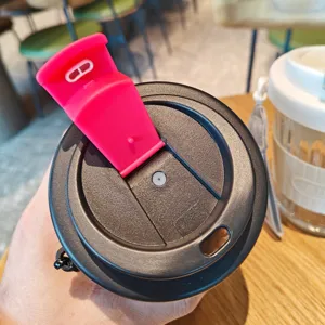 Portable glass coffee cup lid detail with black cover and pink silicone plug for daily use.