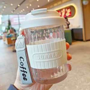 Portable glass coffee cup with silicone sleeve and convenient handle strap for daily use.