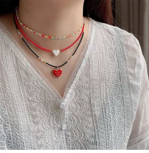 Layered beaded necklace set with colorful seed beads, white shell heart and red love pendant.