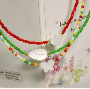 Detailed closeup of multi-layer colorful beaded necklace with shell heart leaf pendants.