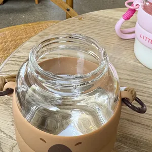 Cute capybara glass water cup with brown silicone sleeve, portable and heat-resistant.