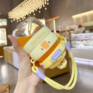 Cute glass straw water cup with silicone sleeve and duckling design, portable with strap.