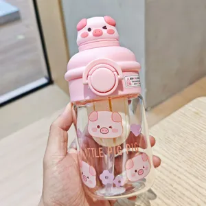 Pink glass water bottle with cute pig lid, straw, and tea infuser for daily hydration use.