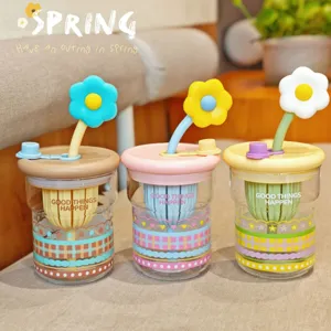 Nahaufnahme Detail der niedlichen Glas-Wasserflasche mit buntem Blumen-Traghalm und Tee.