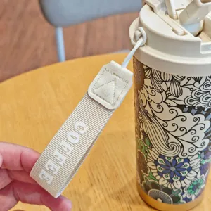 Detalle de correa de taza de café viaje acero boho, vaso térmico portátil vista.