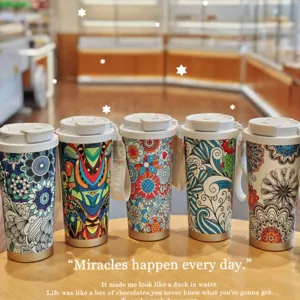 Primer plano de tazas de café térmicas de acero inoxidable con diseño floral bohemio.