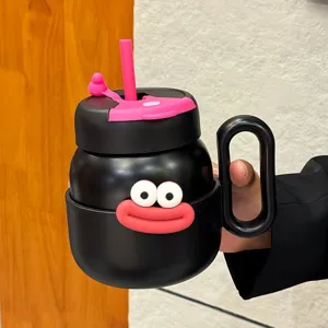 Tazza d'acqua termica nera con simpatico viso di cartone animato, paglia rosa e comodo manico.