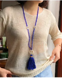 Primo piano dettagliato della lunga collana di perline di cristallo blu con ciondoli pace e nappa.