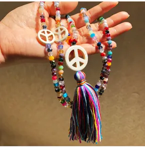 Lunga collana di perline di cristallo con ciondolo simbolo di pace e nappa per donna.