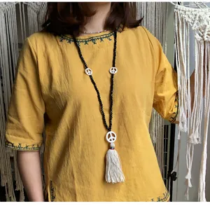 Lunga collana di perle di cristallo con simbolo della pace e nappa per elegante maglione.